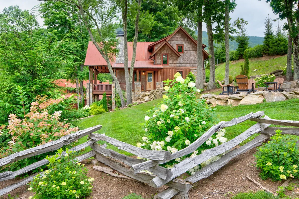 The rustic Storybook Cottage is surrounded by flowering bushes, a wooden fence, and a natural rock seating area. The inviting setup suggests opportunities for outdoor gatherings, relaxing by the fire pit, and enjoying the scenic environment—tying directly to evening activities described in the section.